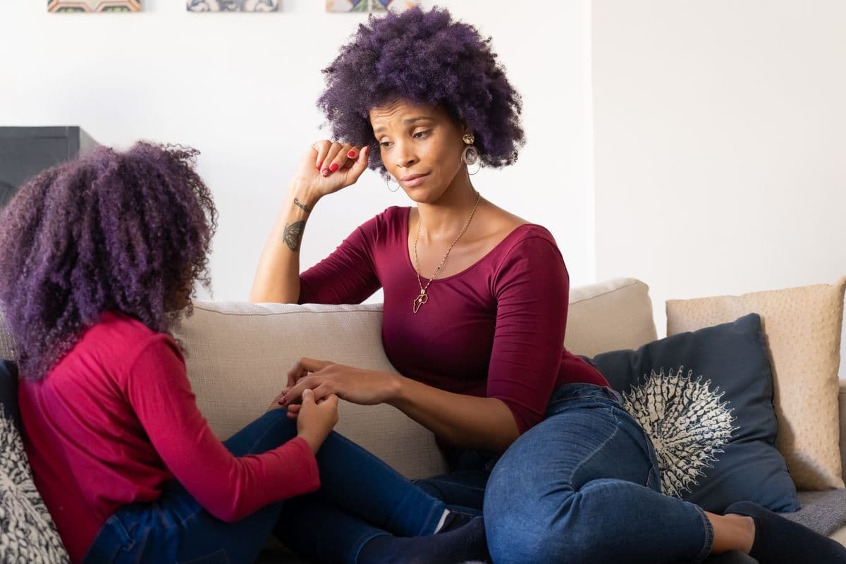 A mother and daughter holding hands during a caring conversation
