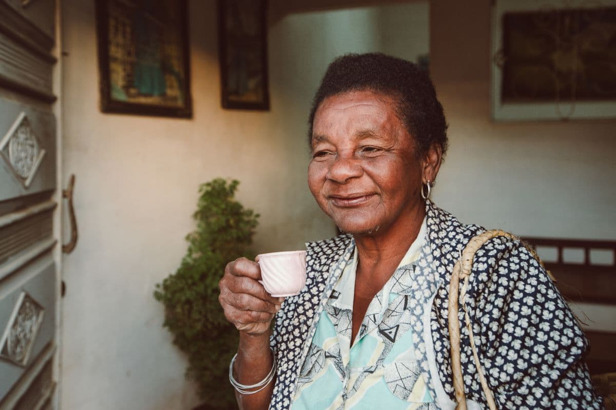 A smiling older woman enjoying a warm cup of tea at home